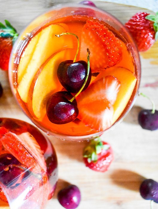 glass of rose sangria with fresh cherries floating on top.