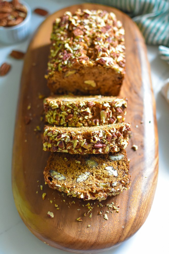 cascading slices of banana pecan bread with rum on wooden serving board.