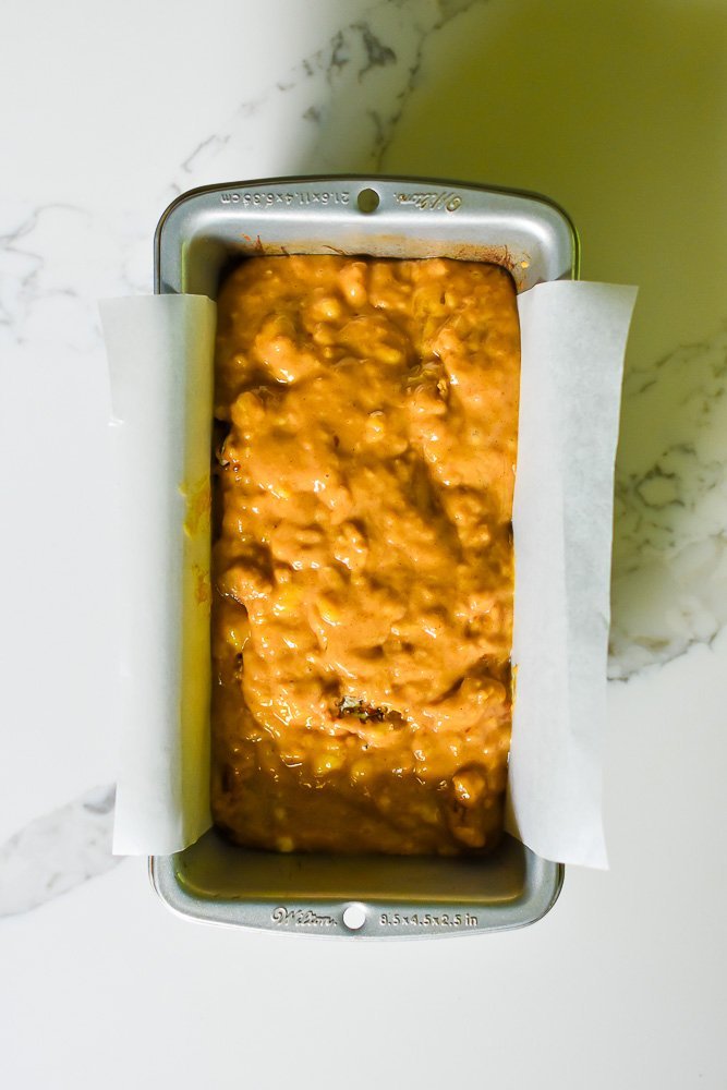 banana rum bread batter in loaf pan lined with parchment paper.
