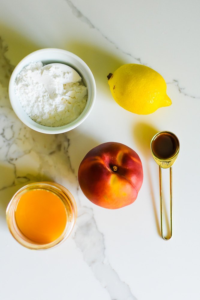 powdered sugar, lemon, vanilla extract, peach, and honey on granite counter top.
