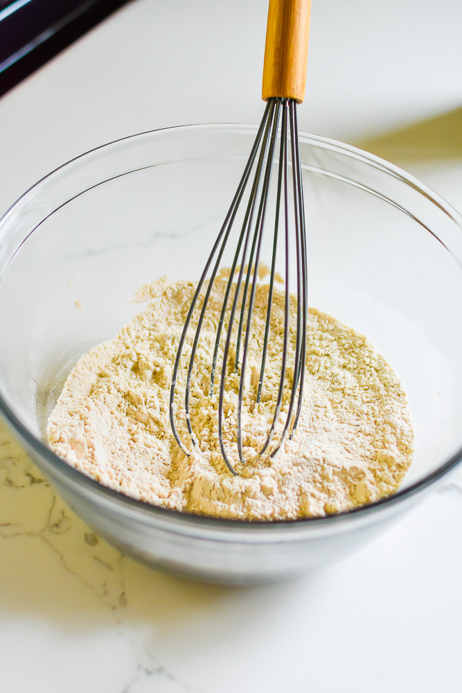 dry peanut butter cookie ingredients in mixing bowl with whisk.