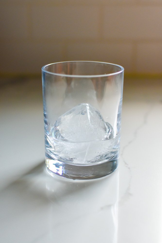 gin in rocks glass over large ice cube.