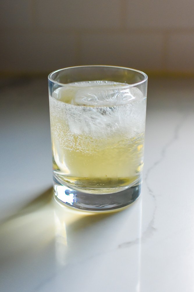 tonic water, apple cider, and gin in rocks glass over large ice cube.