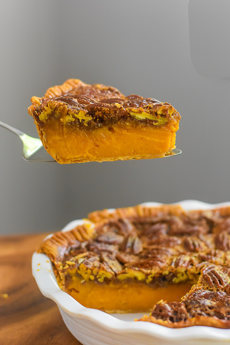 slice of layered sweet potato pecan pie with bourbon on silver serving spatula.