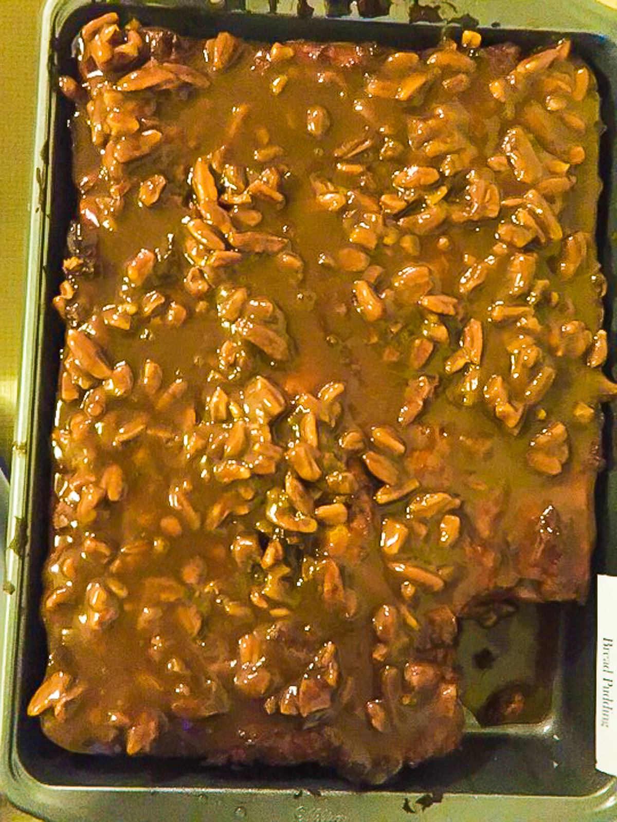 large pan of sweet potato bread pudding covered in decadent praline sauce and pecans.