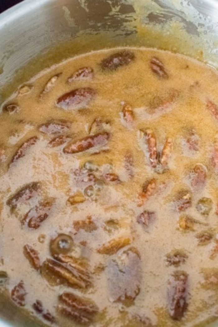pecan praline sauce in saucepan with halved pecans stirred in.
