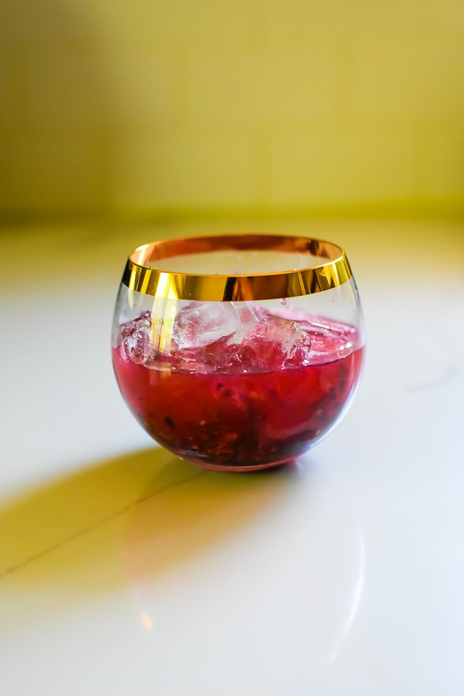 mixed berry bourbon smash mixture and ice in rounded rocks glass.