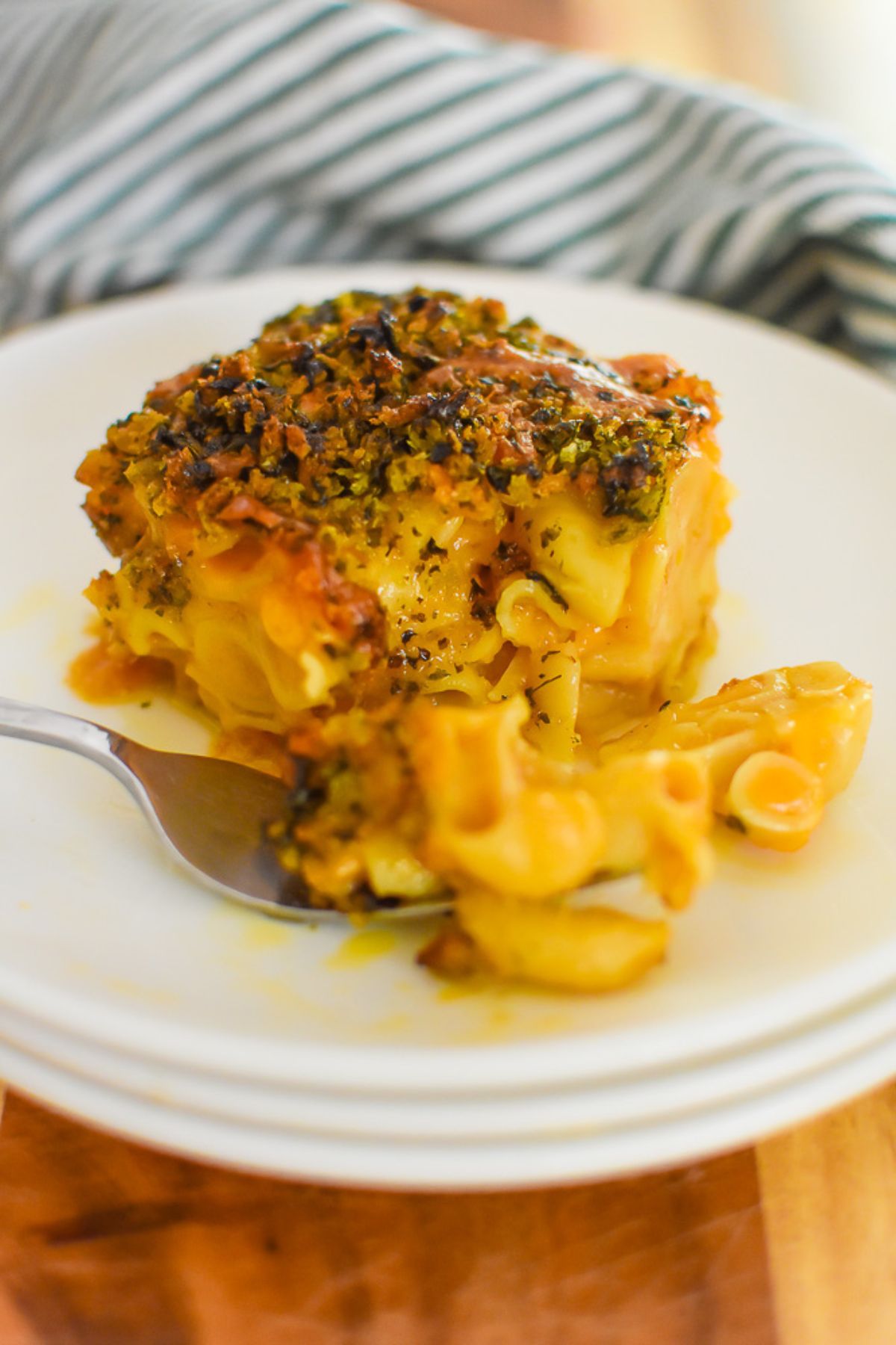 cheesy gooey square of brown butter baked mac and cheese with herbed bread crumb topping on stack of three saucers.