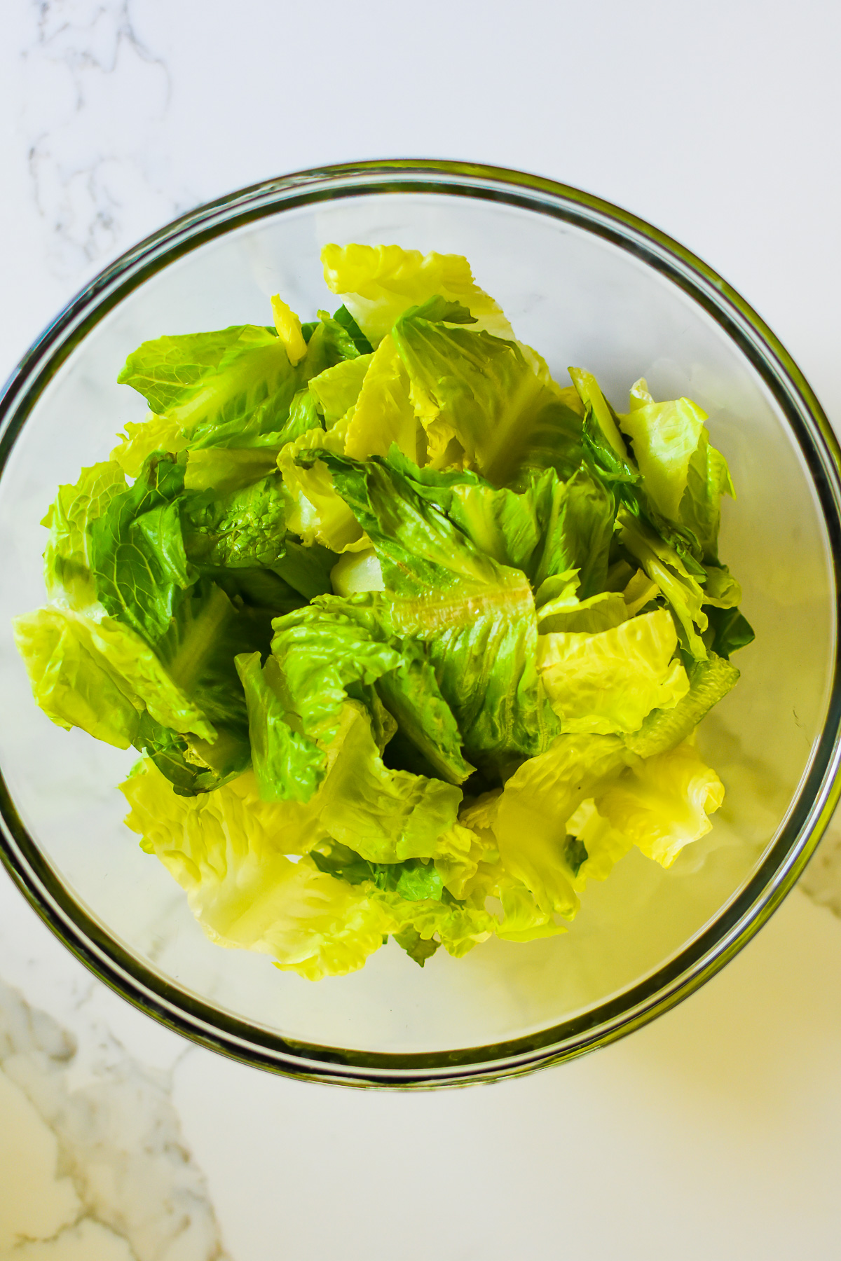 chopped and rinsed romaine lettuce leaves in glass mixing bowl.