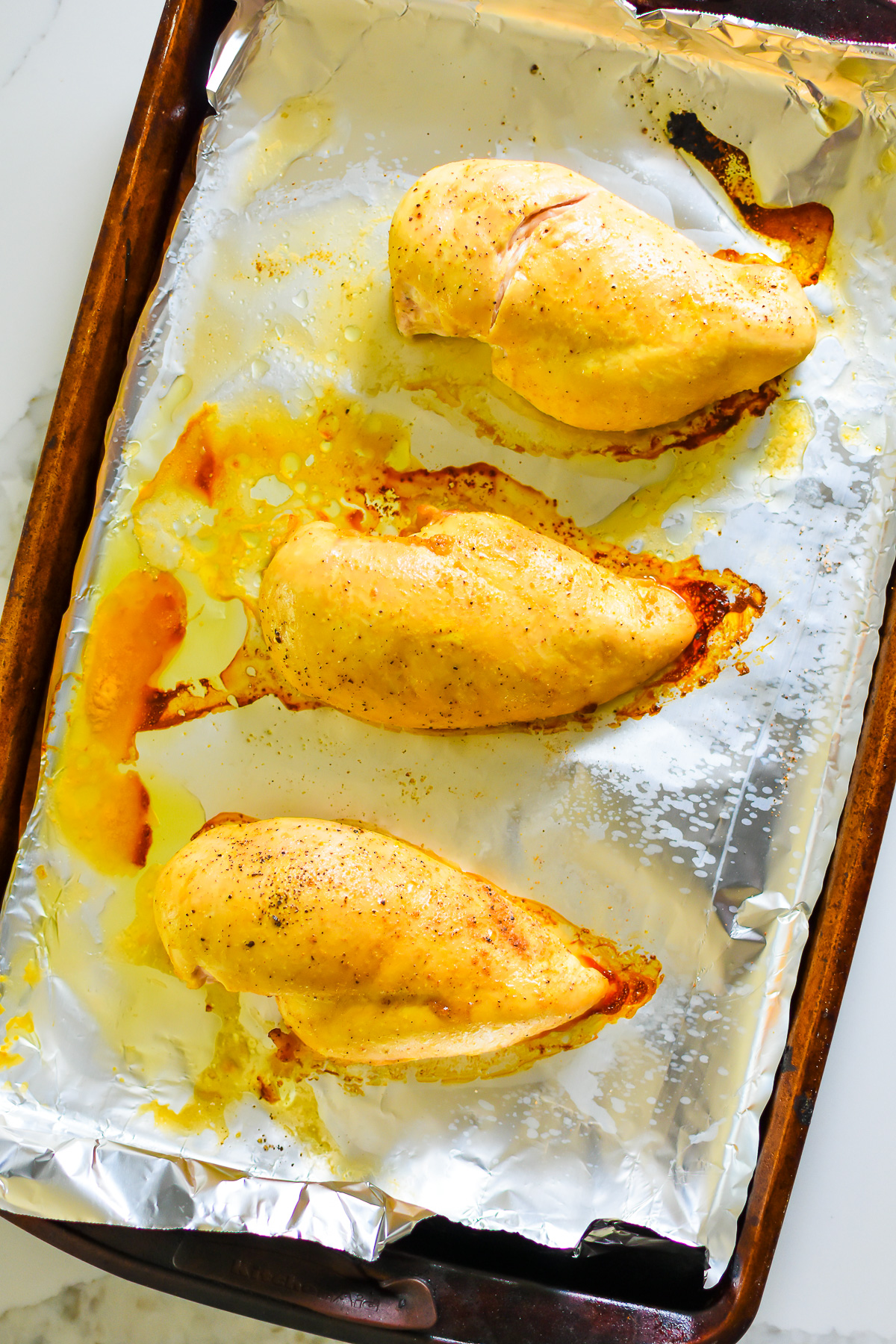 seasoned roasted chicken breasts on foil lined sheet pan.