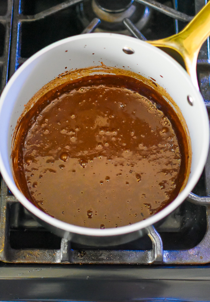 thick and rich bubbling gingerbread spiced hot chocolate in small saucepan on hot stove.