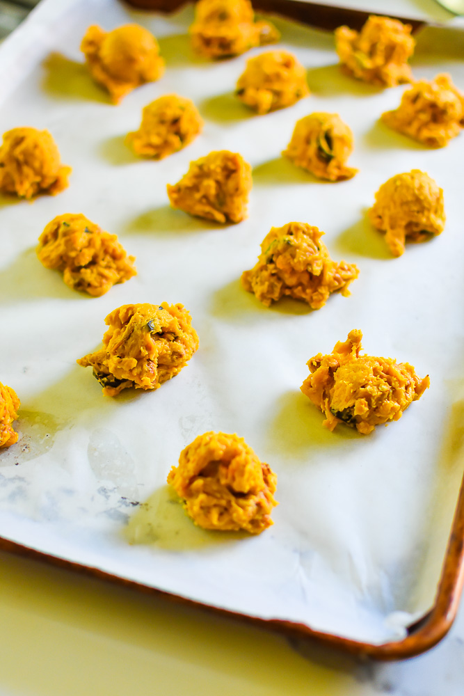 balls of pumpkin kitchen sink cookie dough on parchment lined cookie sheet.