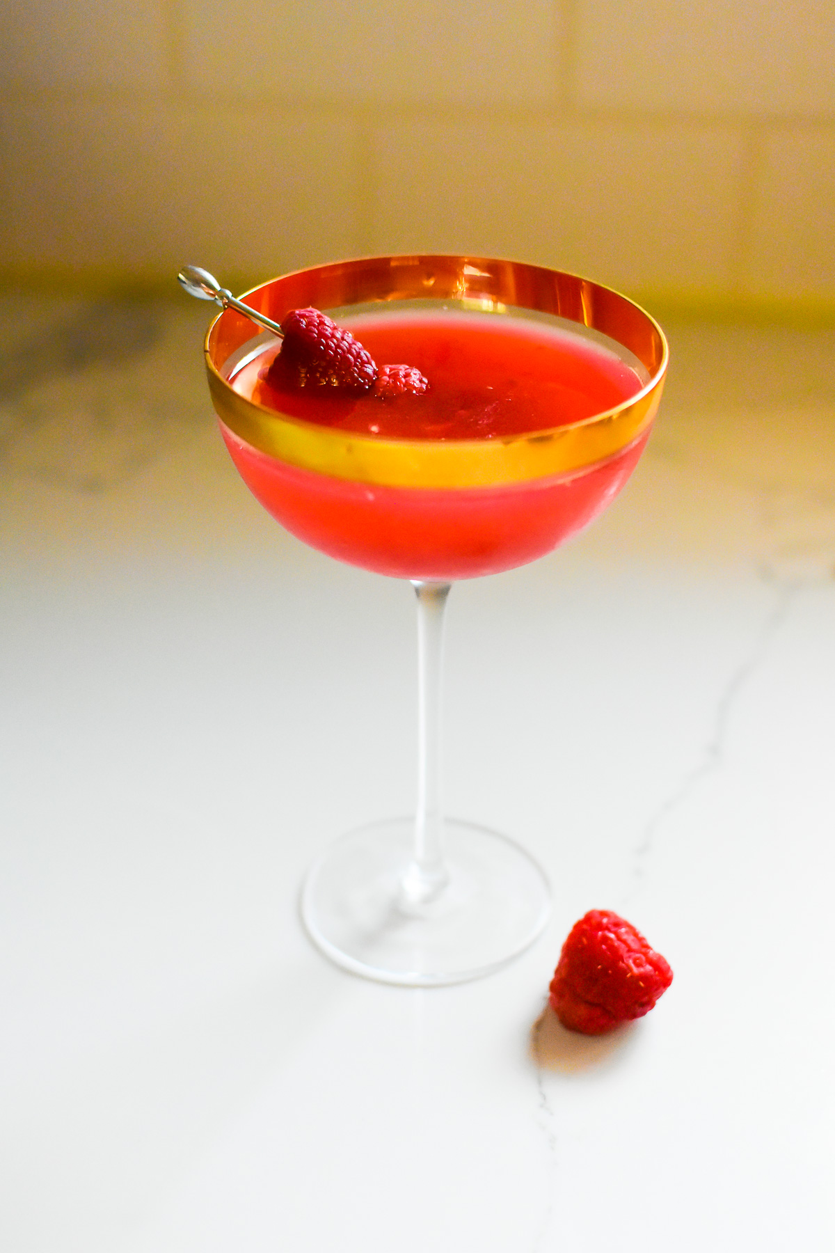 deliciously smooth raspberry martini with Chambord and gin in a gold rimmed coupe glass and garnished with fresh raspberries.