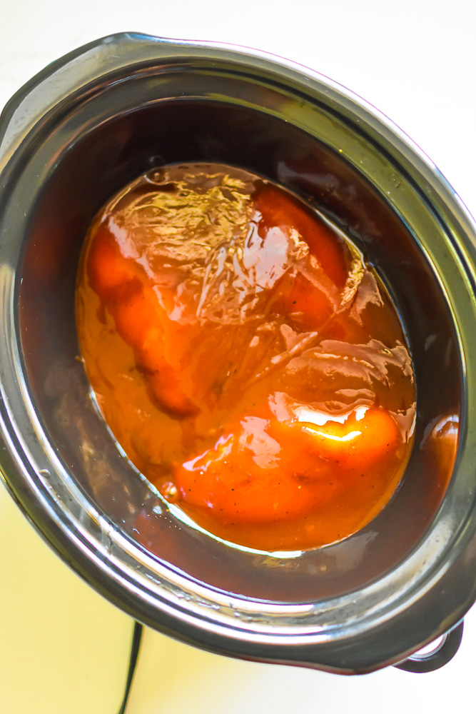 chicken breast covered with barbecue sauce in crockpot.