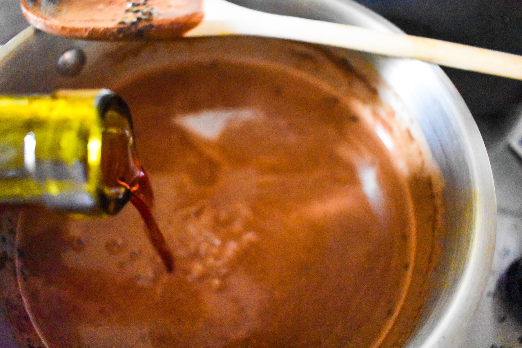 pouring sweet red wine into pot of hot cocoa.