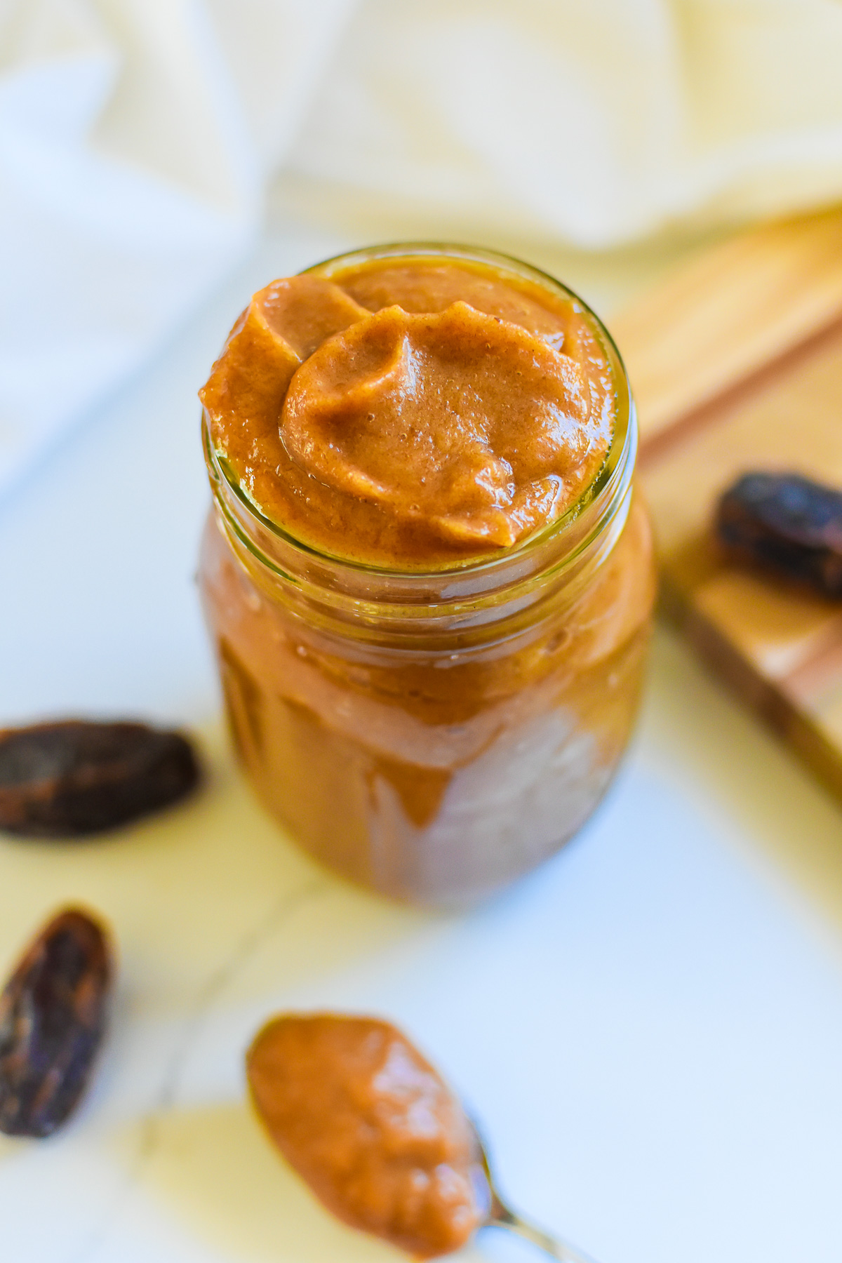 the best date paste made with just medjool dates and water in a small mason jar surrounded by more dates.