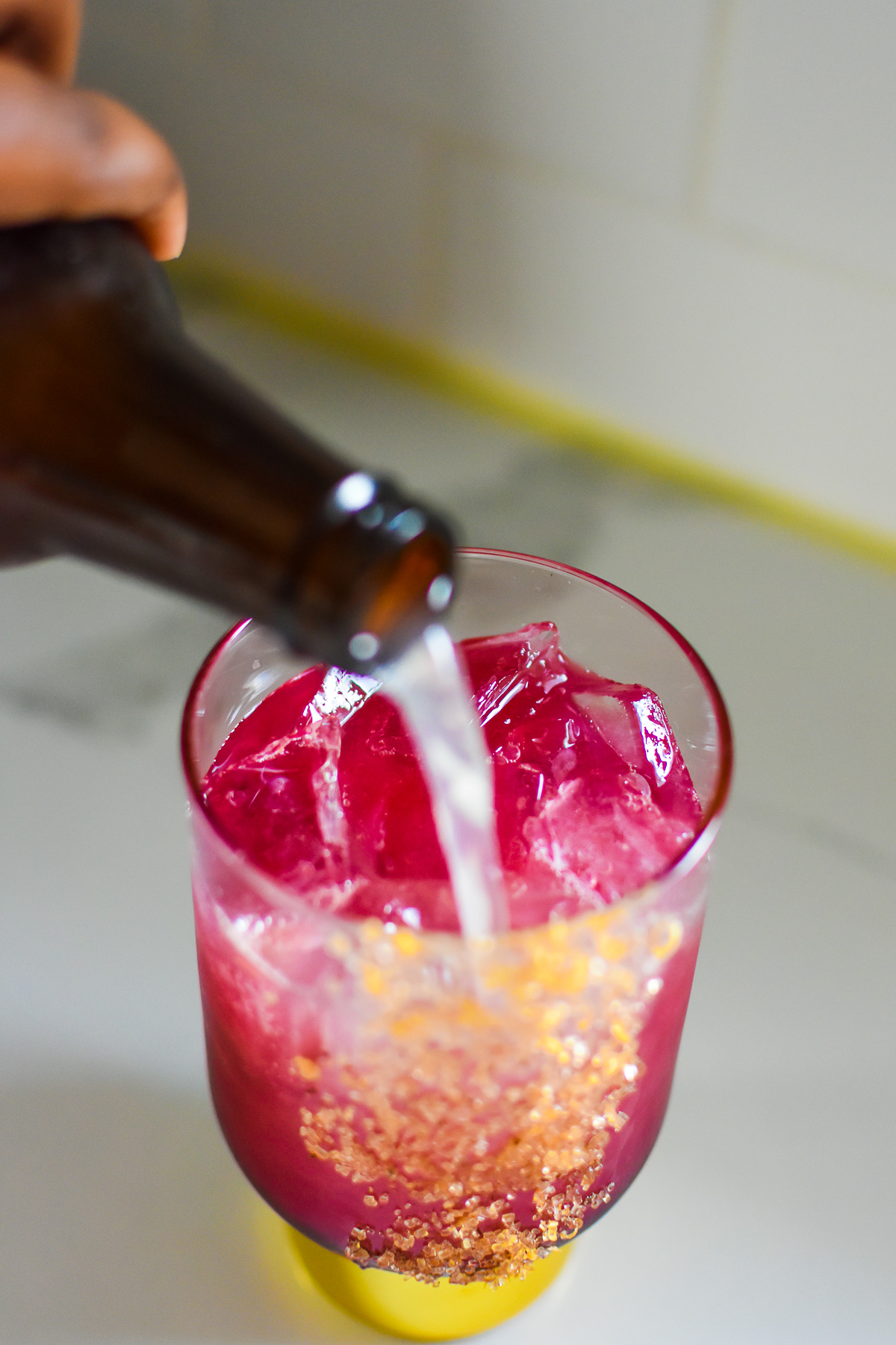 pour ginger beer into pomegranate Christmas mocktail.