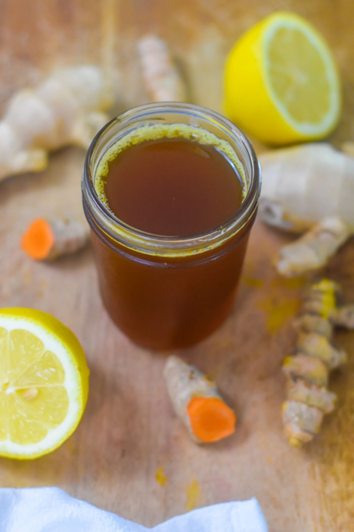 small jar of homemade ginger turmeric honey syrup infused with fresh lemon, clove, and black pepper for immune support and antioxidant supplementation.