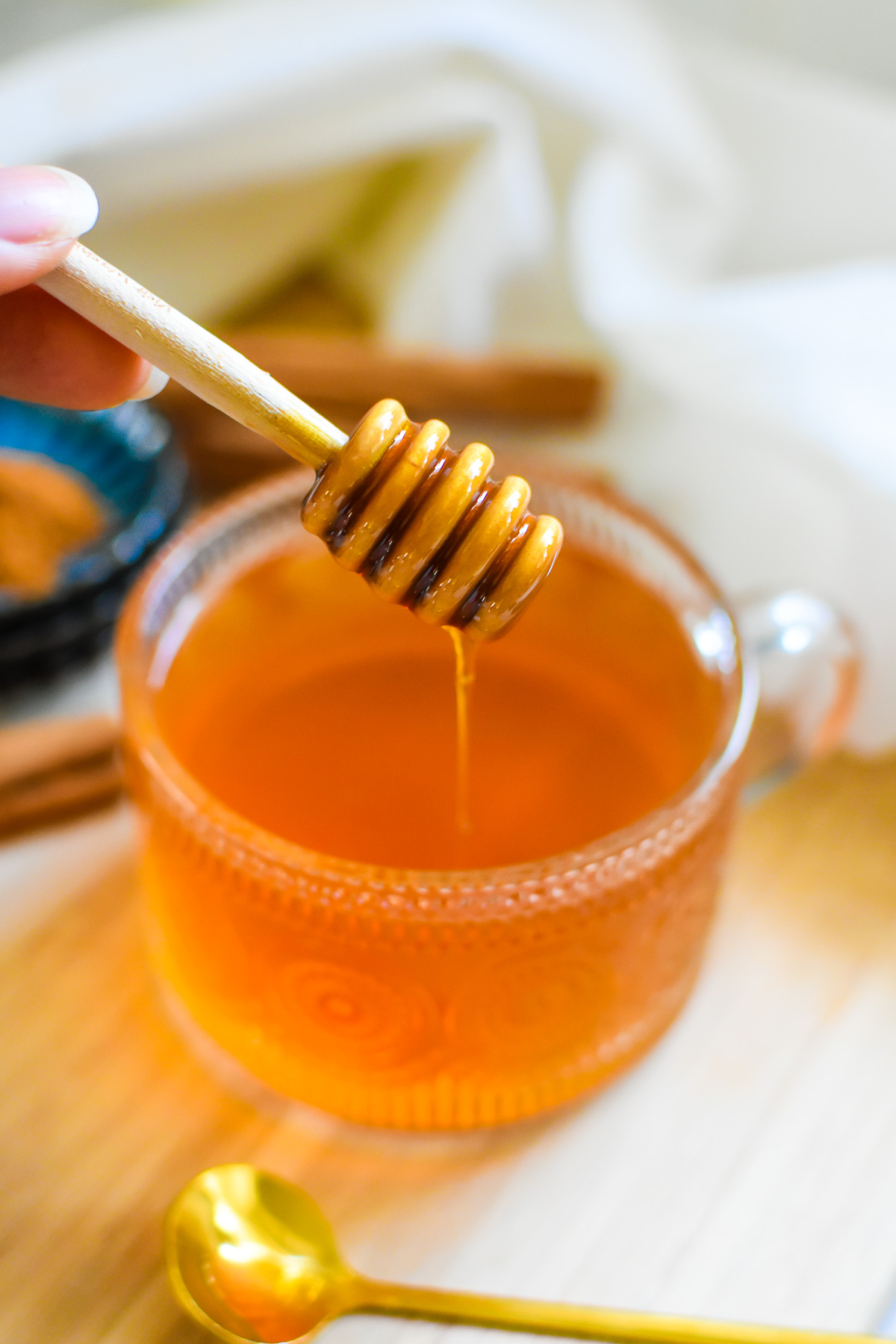 adding honey drizzle to mug of steaming cinnamon tea.