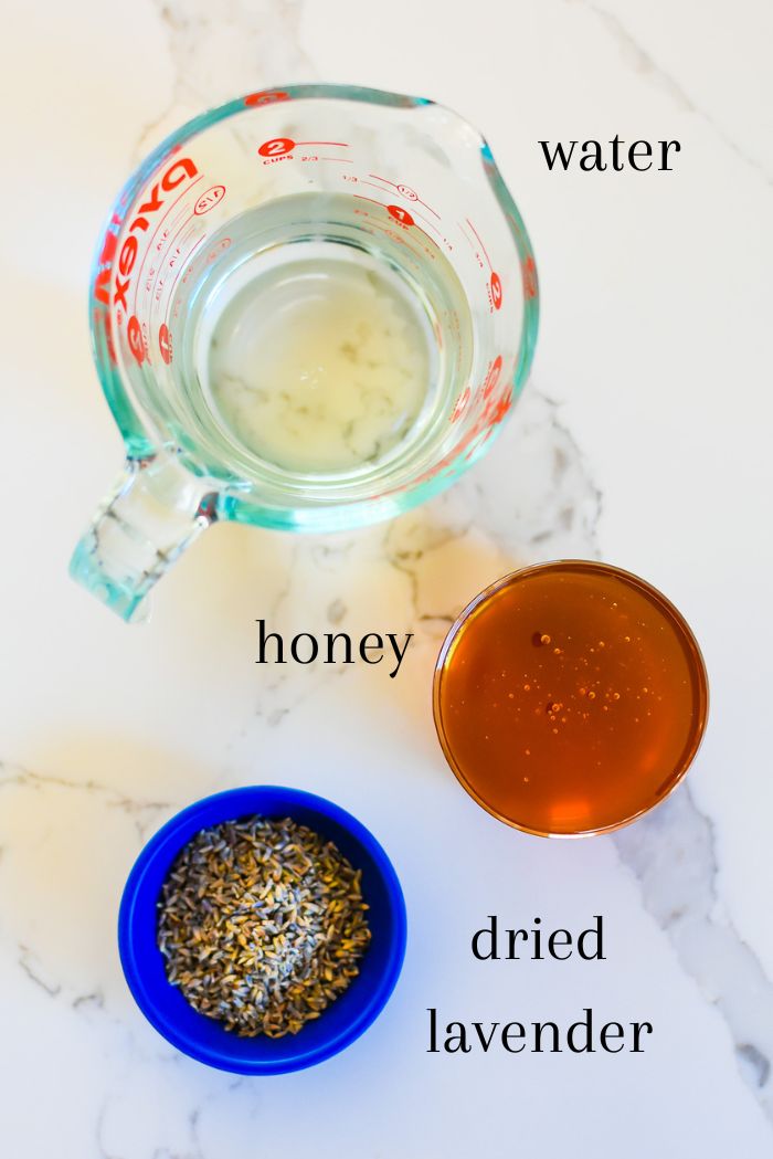ingredients to make DIY lavender honey syrup on granite countertop: water, honey, dried culinary grade lavender.