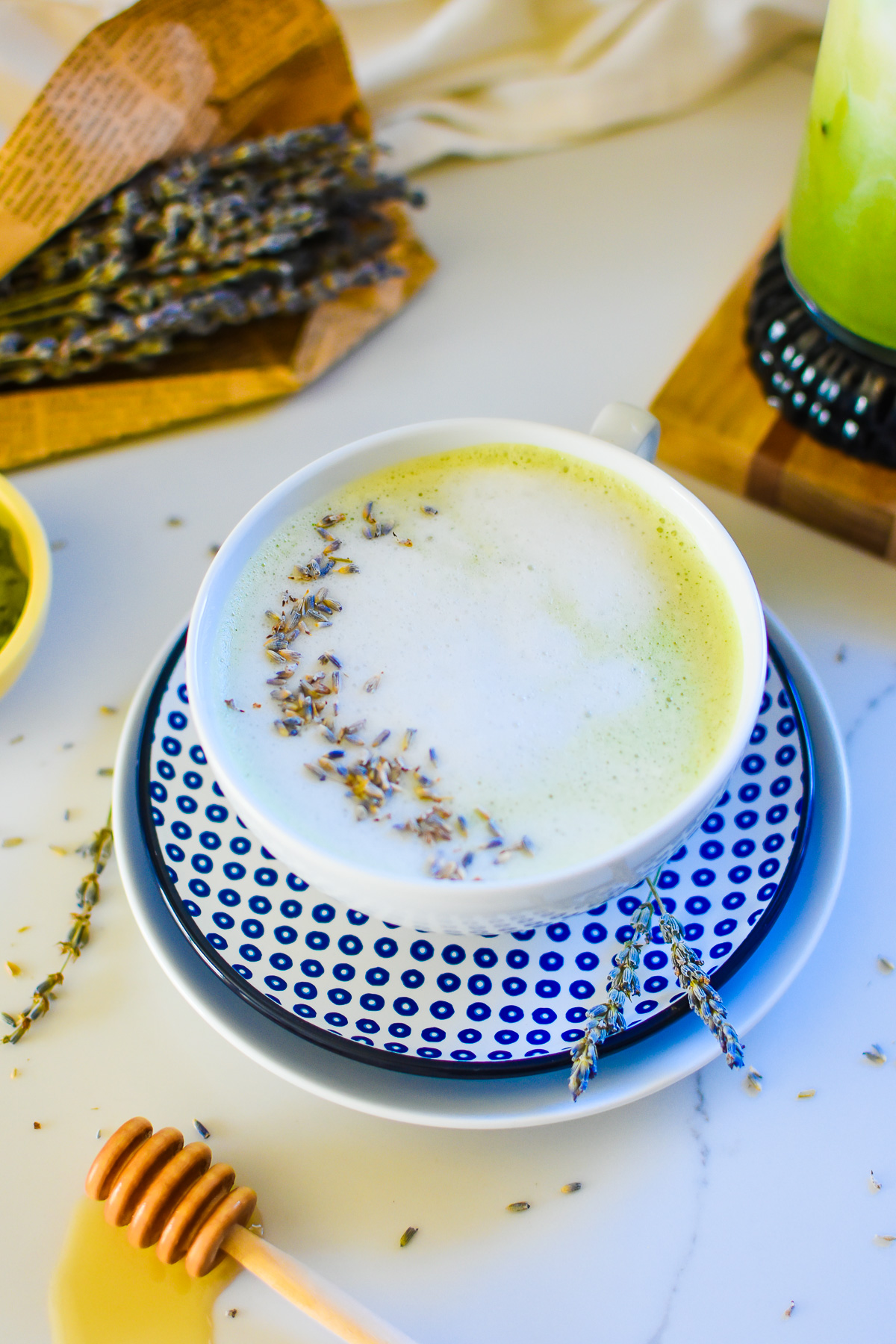 DIY honey lavender matcha latte made with almond milk and served in white teacup on blue and white sauces.
