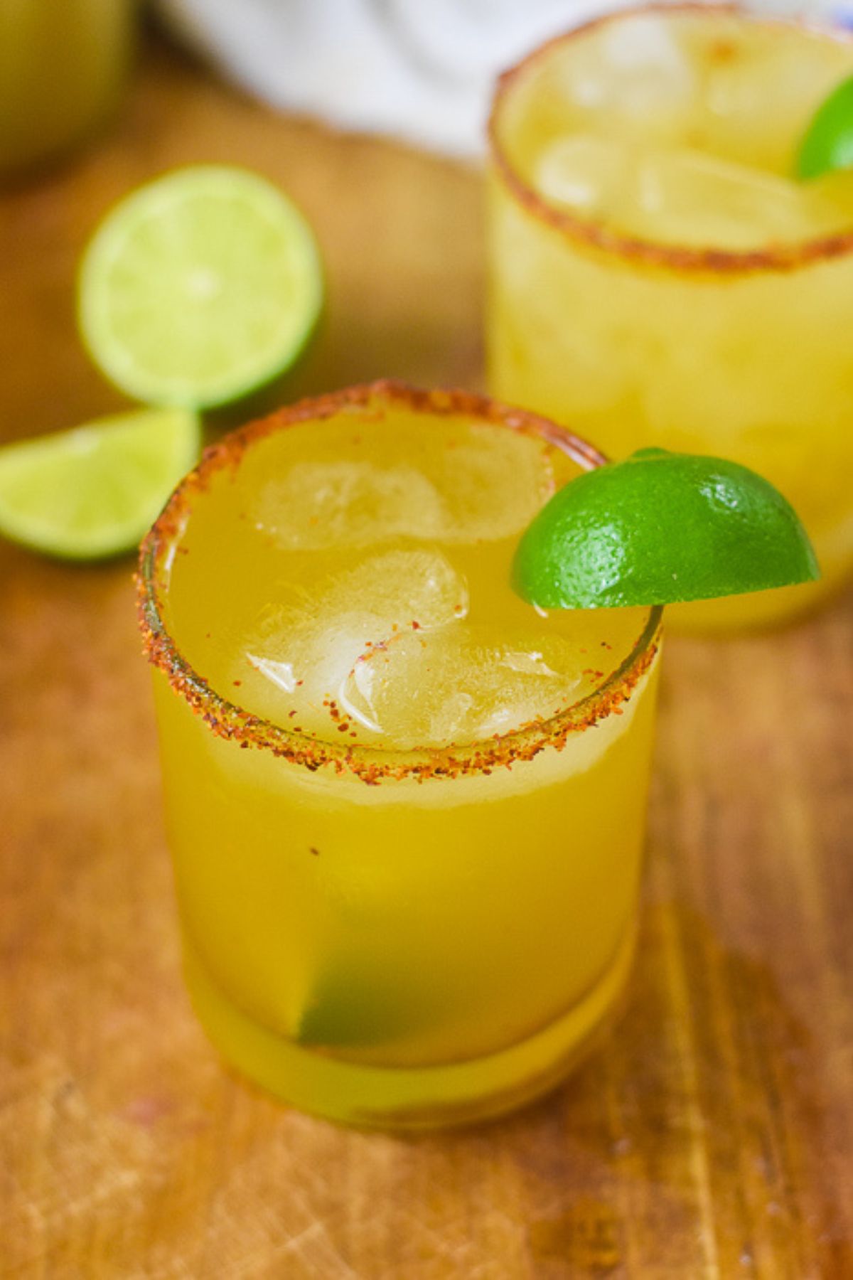 the best spicy passion fruit margarita served on the rocks with a Mexican chili spice rim and lime wedge garnish.