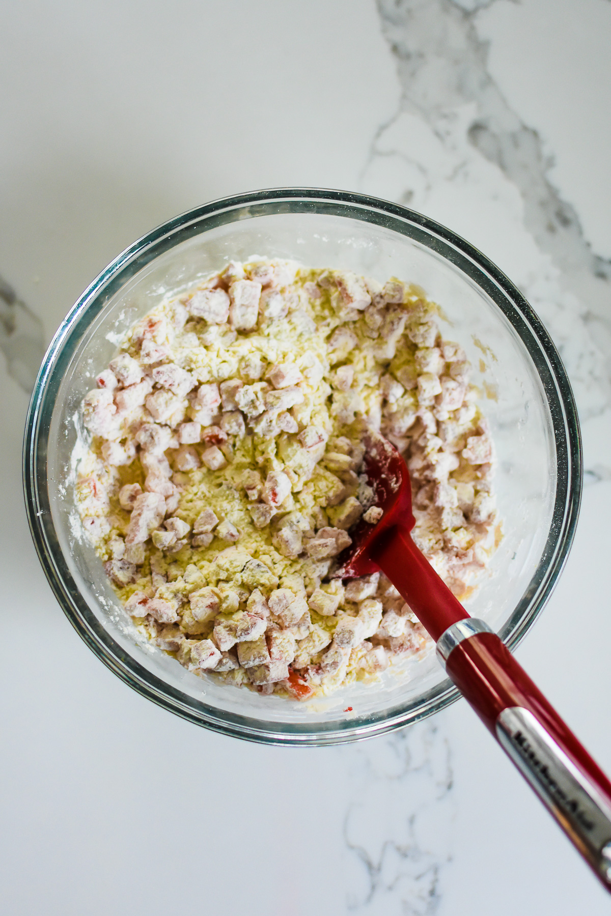 strawberry pieces mixed into flour in glass bowl