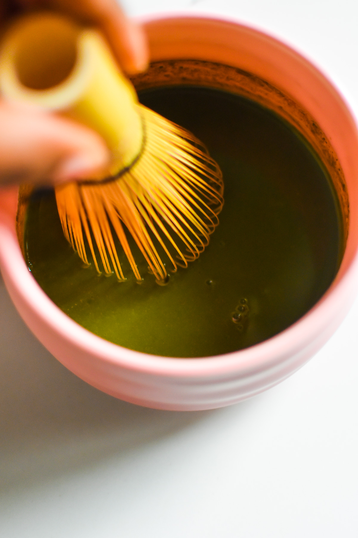 dissolving cinnamon, matcha powder, and honey in hot water with bamboo whisk.