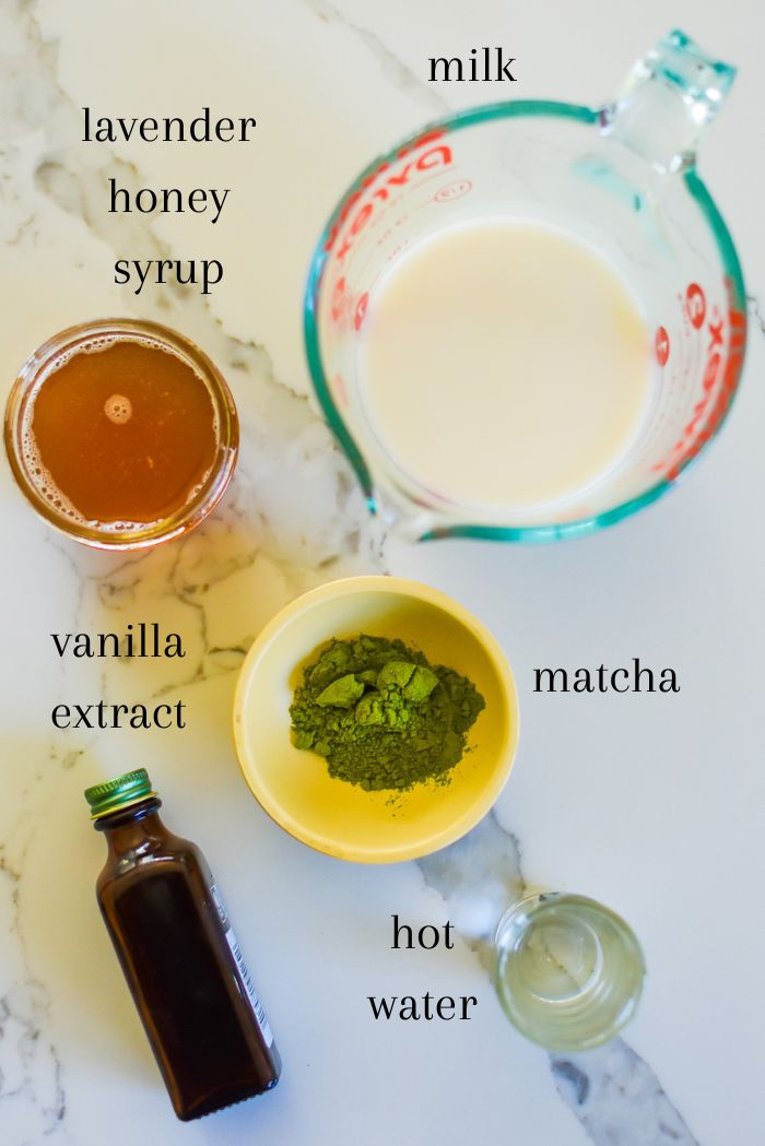ingredients to make the best lavender matcha at home on counter top, including milk, lavender honey syrup, vanilla extract, ceremonial grade matcha powder, and hot water.
