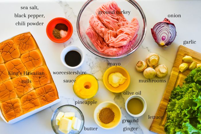 ingredients to make easy turkey burger sliders on granite countertop, including King's Hawaiian rolls, ground turkey, pineapple rings, spices, and Worcestershire sauce.