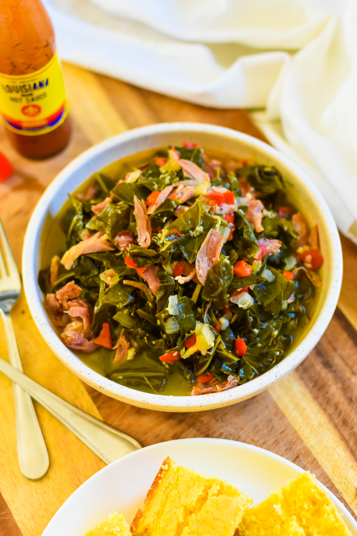 The best old school Soul Food collard greens with smoked turkey and red bell pepper served in a stone bowl swimming in pot likker.