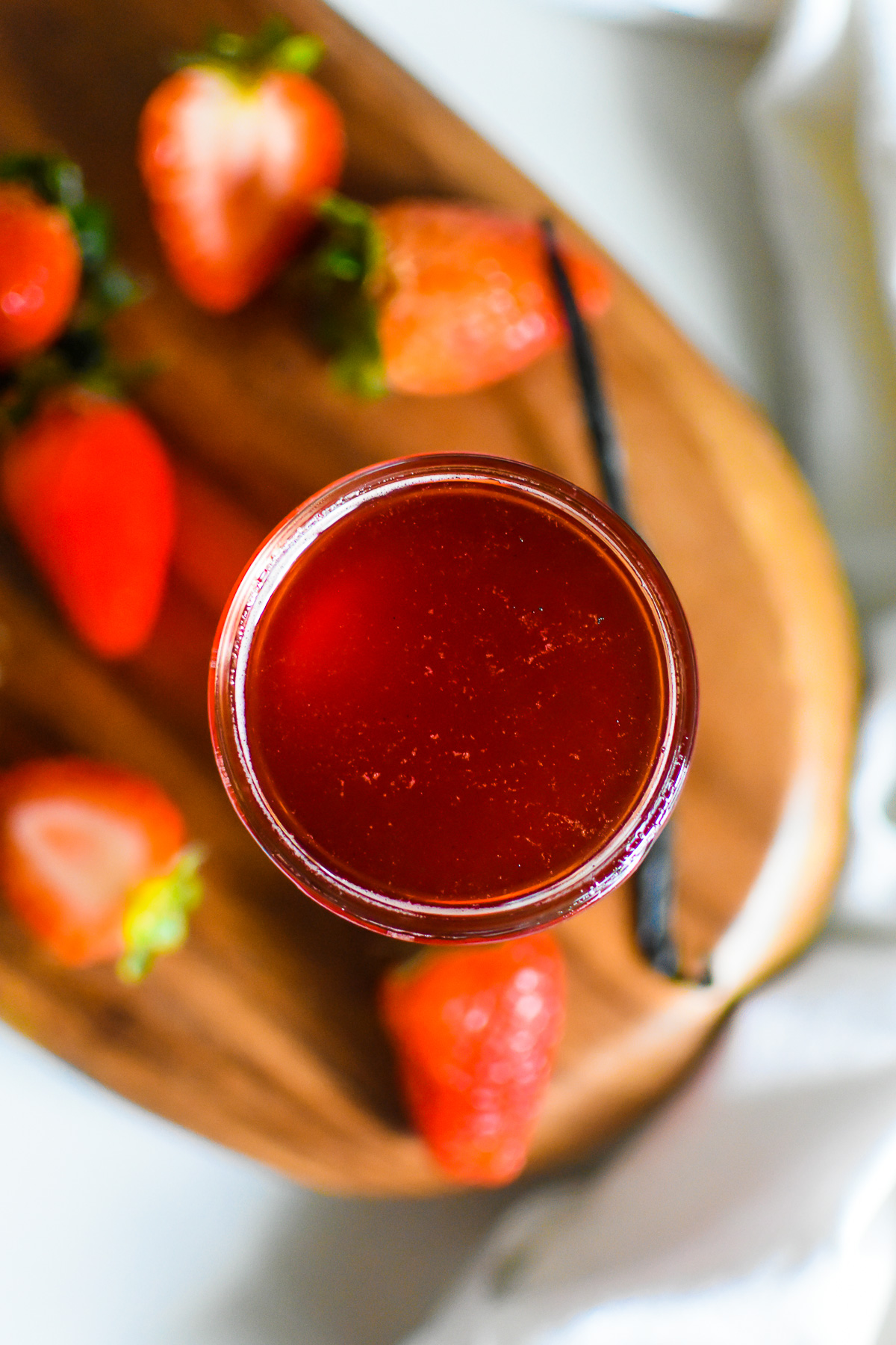 the best homemade strawberry simple syrup in a glass jar made with vanilla bean, fresh strawberries, and two other easy ingredients to use in drinks, on cakes, ice cream, and more.