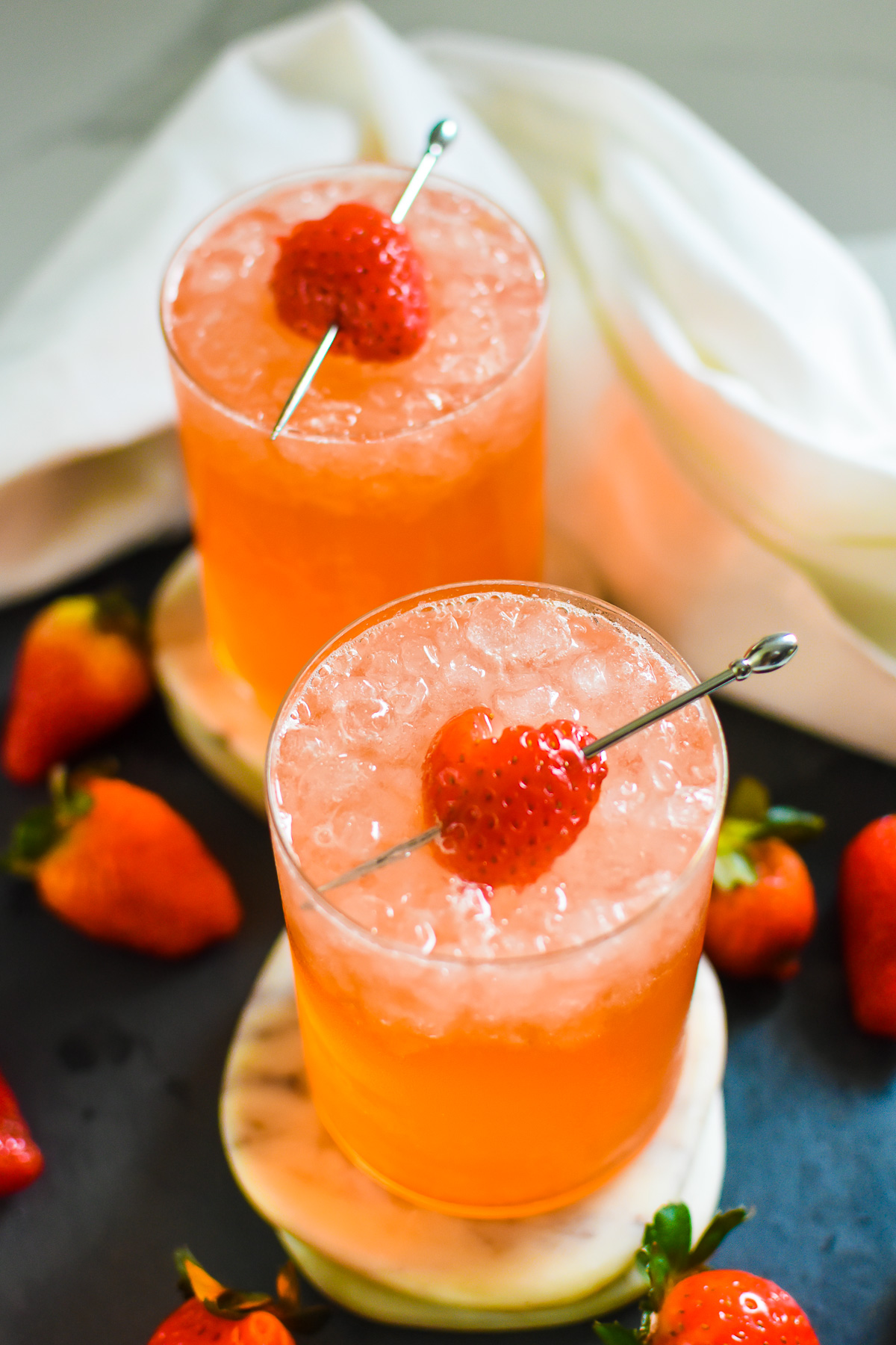 The best easy and homemade Valentine's Day mocktail served over crushed ice in a modern highball glass and surrounded by fresh strawberries.