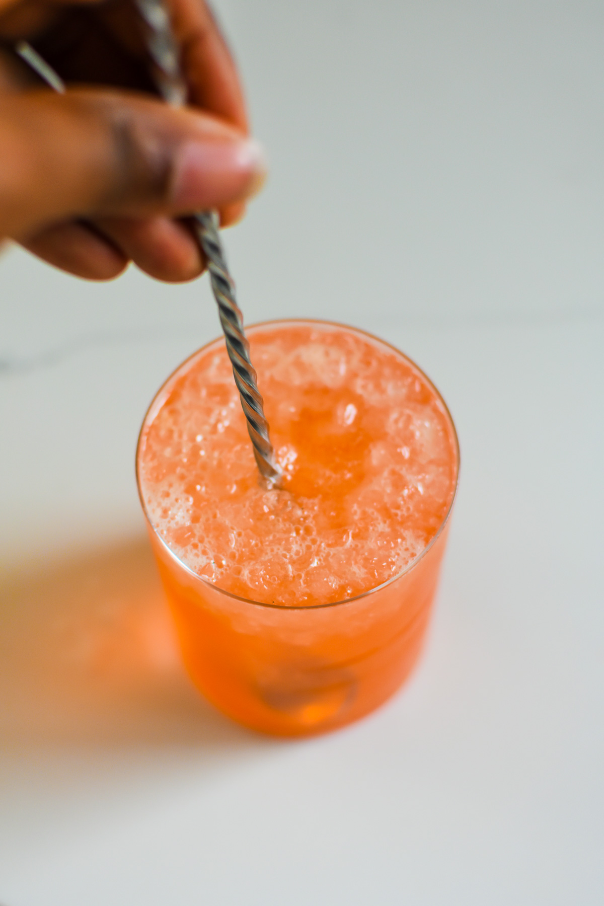 stirring non alcoholic pink mocktail with bar spoon.