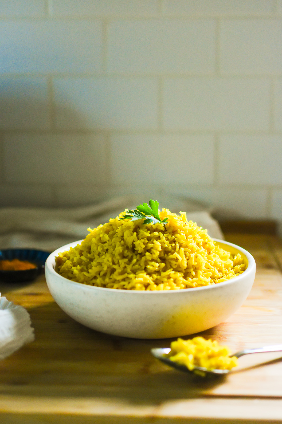 bowl of fluffy, savory yellow rice garnished with parsley.