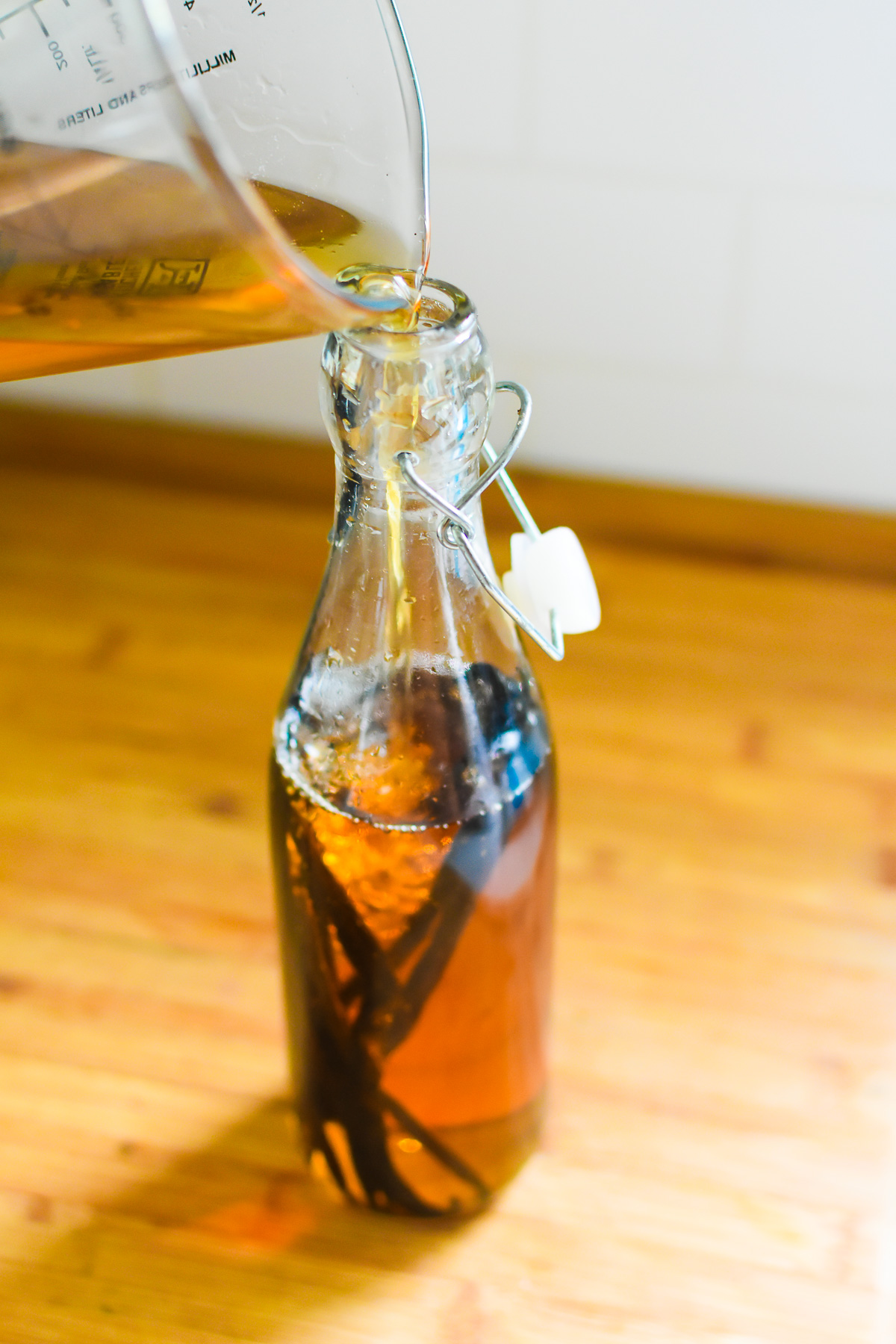 pouring good bourbon whiskey into a glass bottle with vanilla beans.