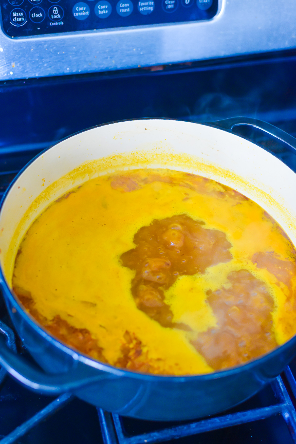 boiling pumpkin soup made with pumpkin puree in Dutch oven on stove top.