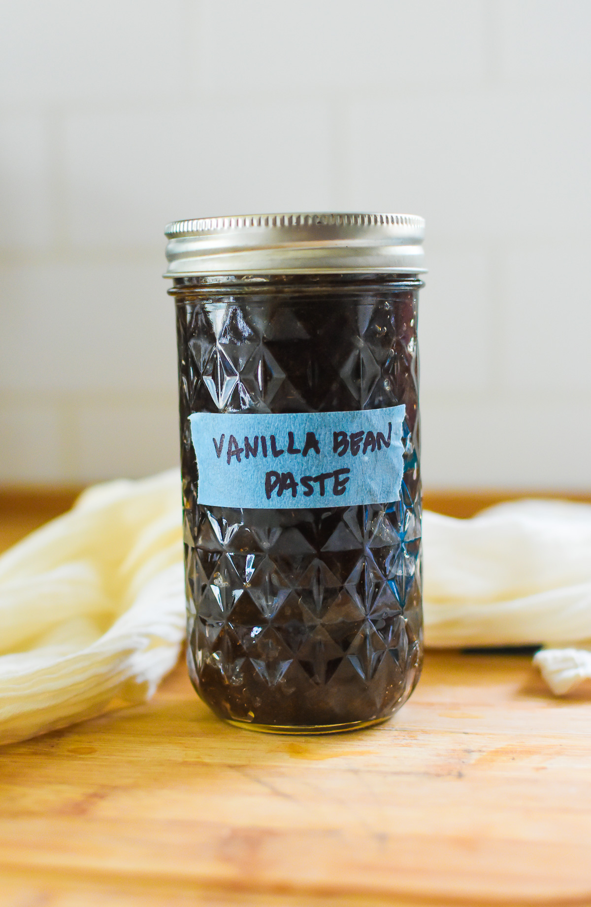 jelly jar of bourbon vanilla bean paste labeled with a strip of blue tape.