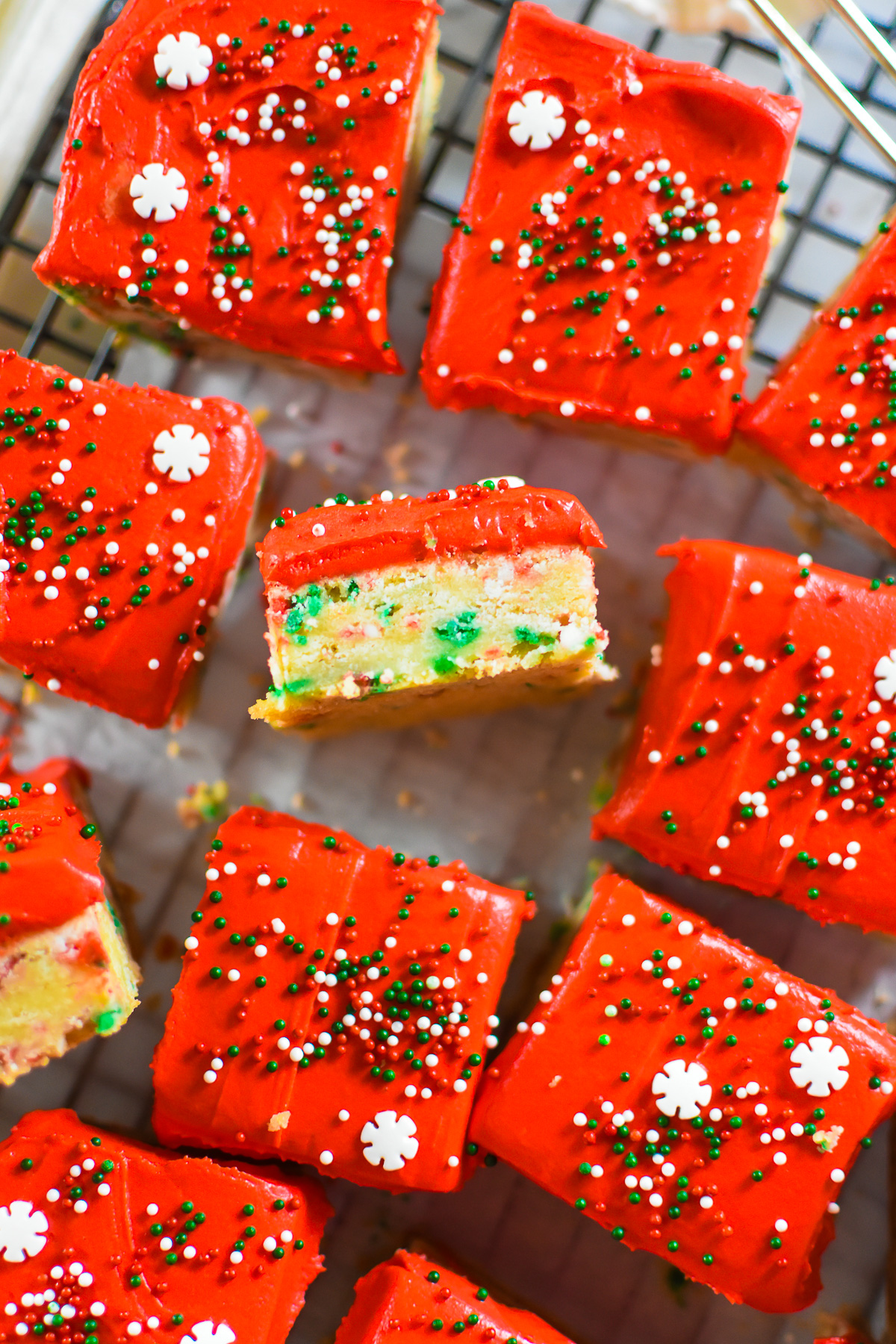 homemade christmas sprinkle sugar cookie bars iced with red frosting.