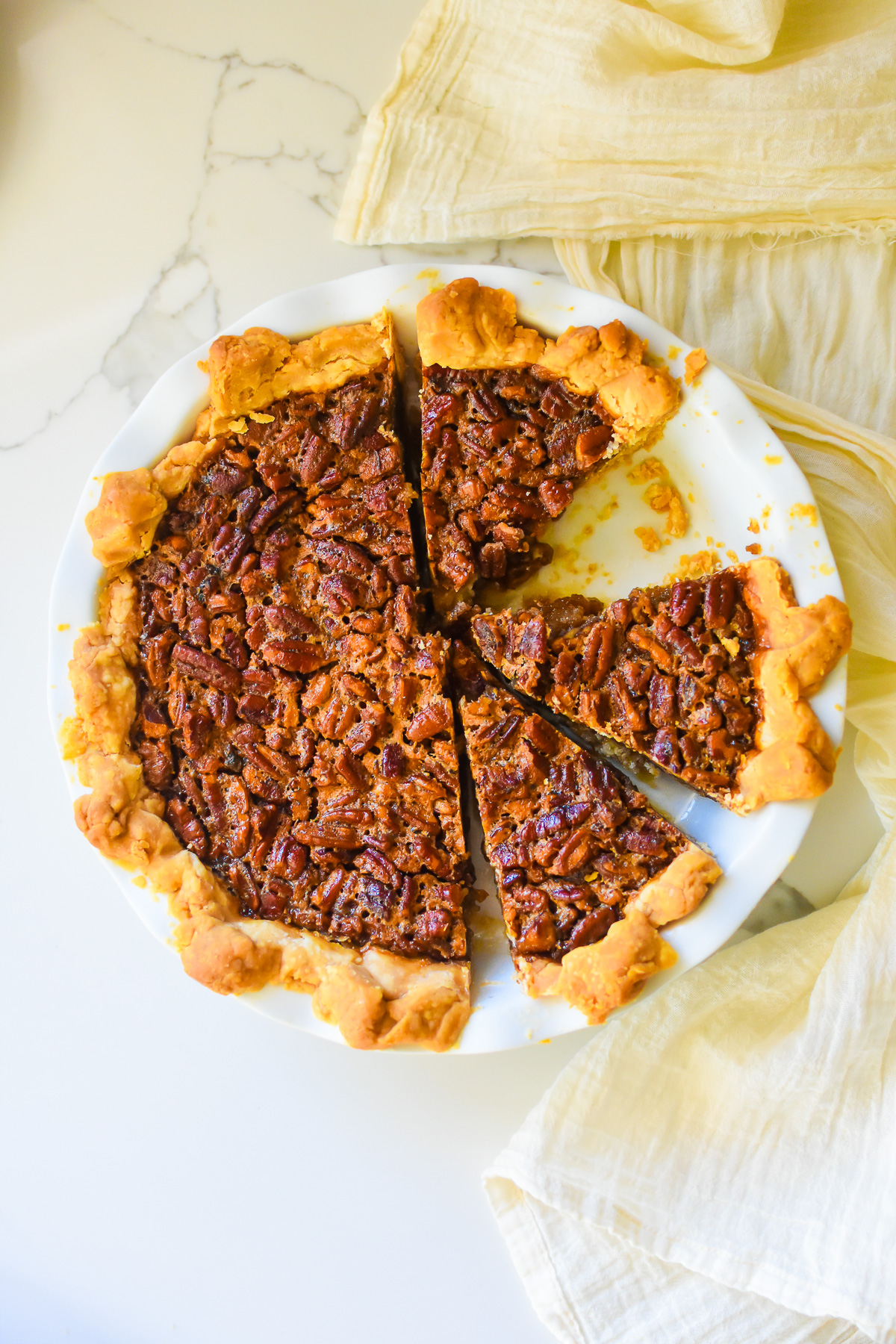 slices of southern pecan pie with made with light corn syrup in a white fluted pie plate.
