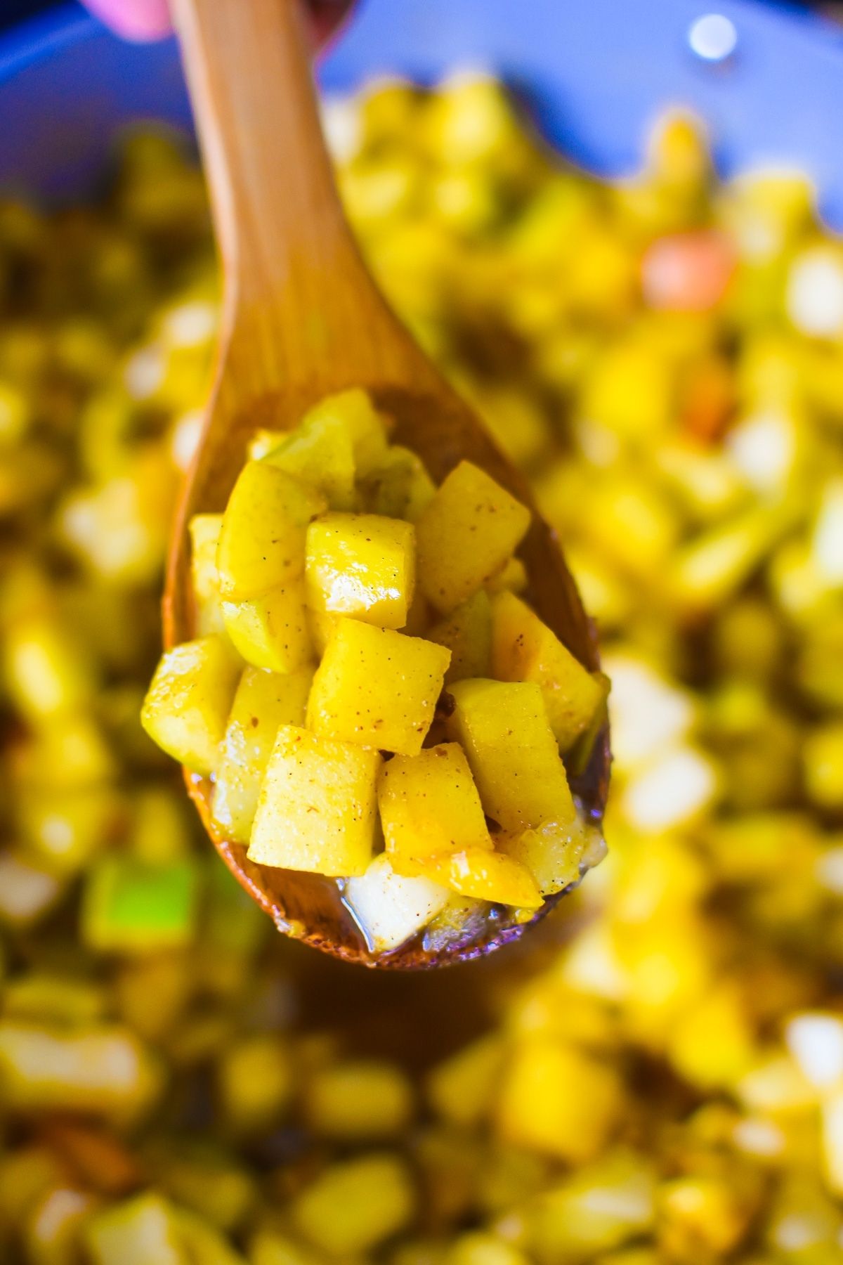 cooked pears on stove scooped up with a wooden kitchen spoon.