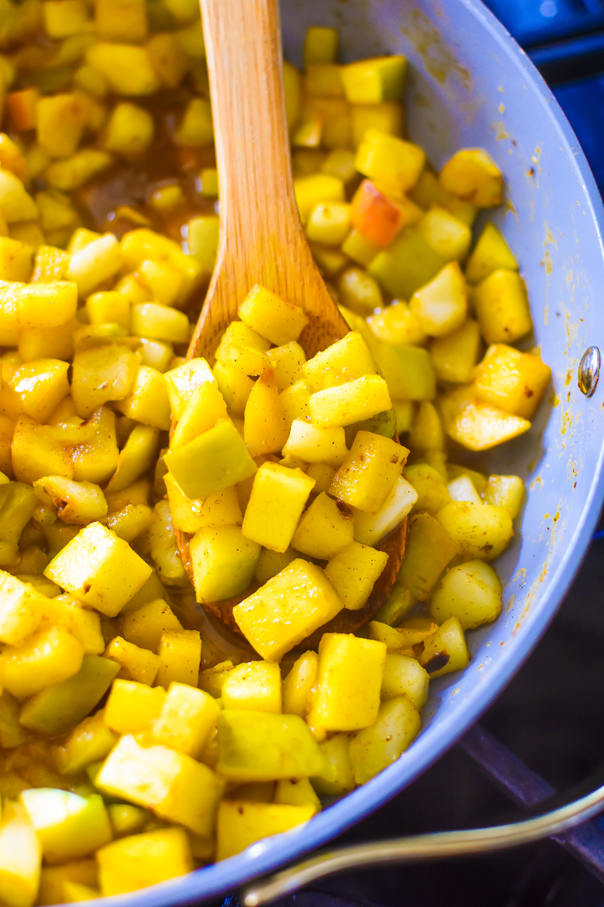 tender, golden stewed apples in a saucepan with a wooden kitchen spoon.