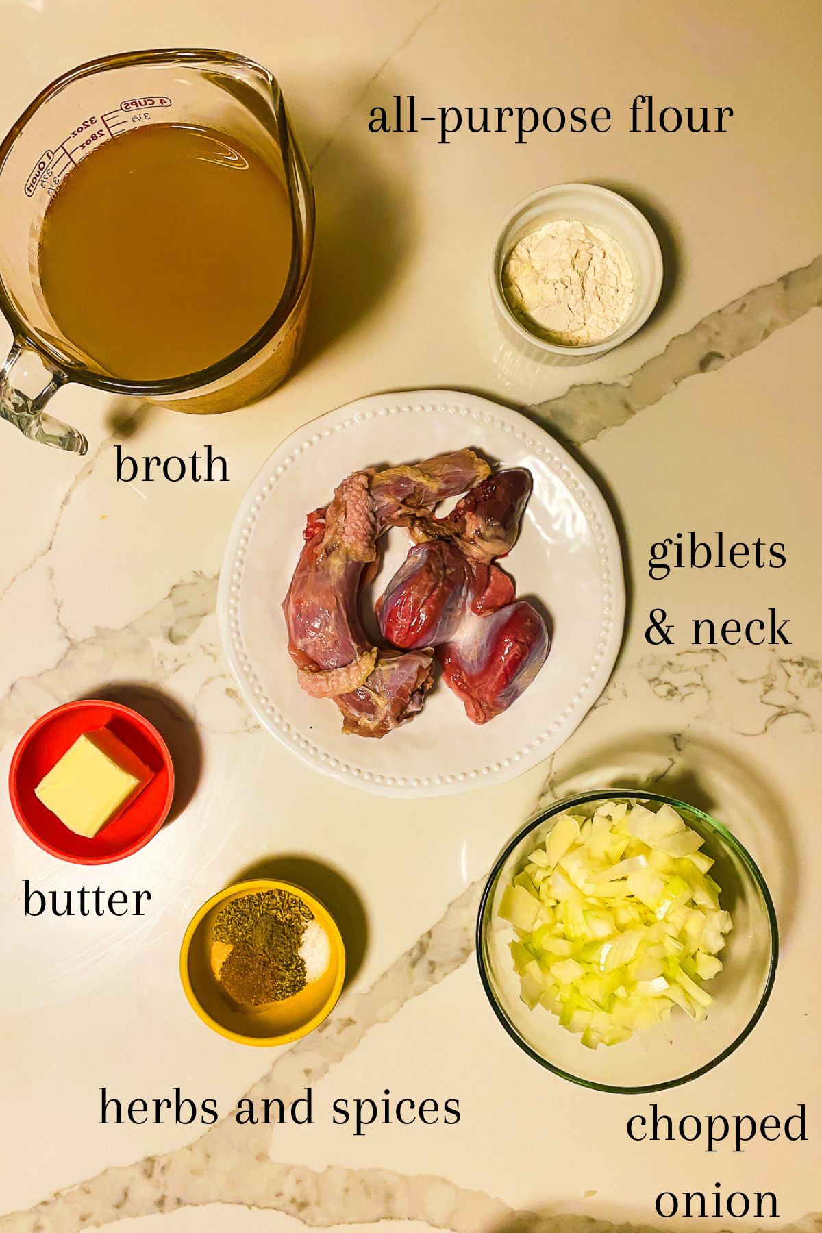 ingredients for a giblet stock gravy recipe on granite counter top: chicken broth, all-purpose flour, unsalted butter, herbs and spices, turkey giblets with turkey neck, and chopped yellow onion.