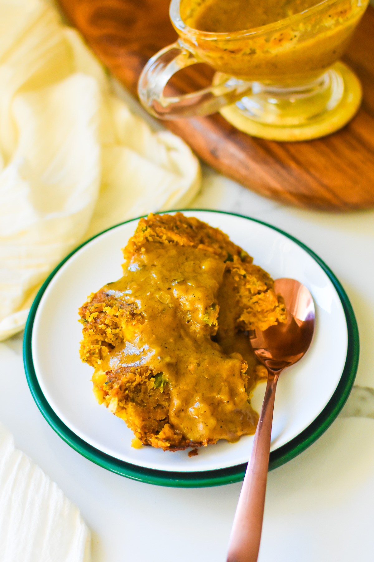 turkey gravy using giblets served over down South cornbread dressing on a white saucer with a copper spoon.