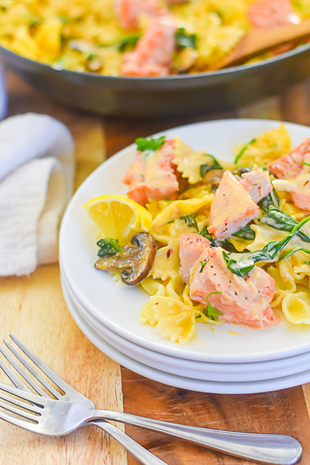 bowtie pasta with pieces of roasted salmon mushroom slices, and sautéed spinach in cream sauce.