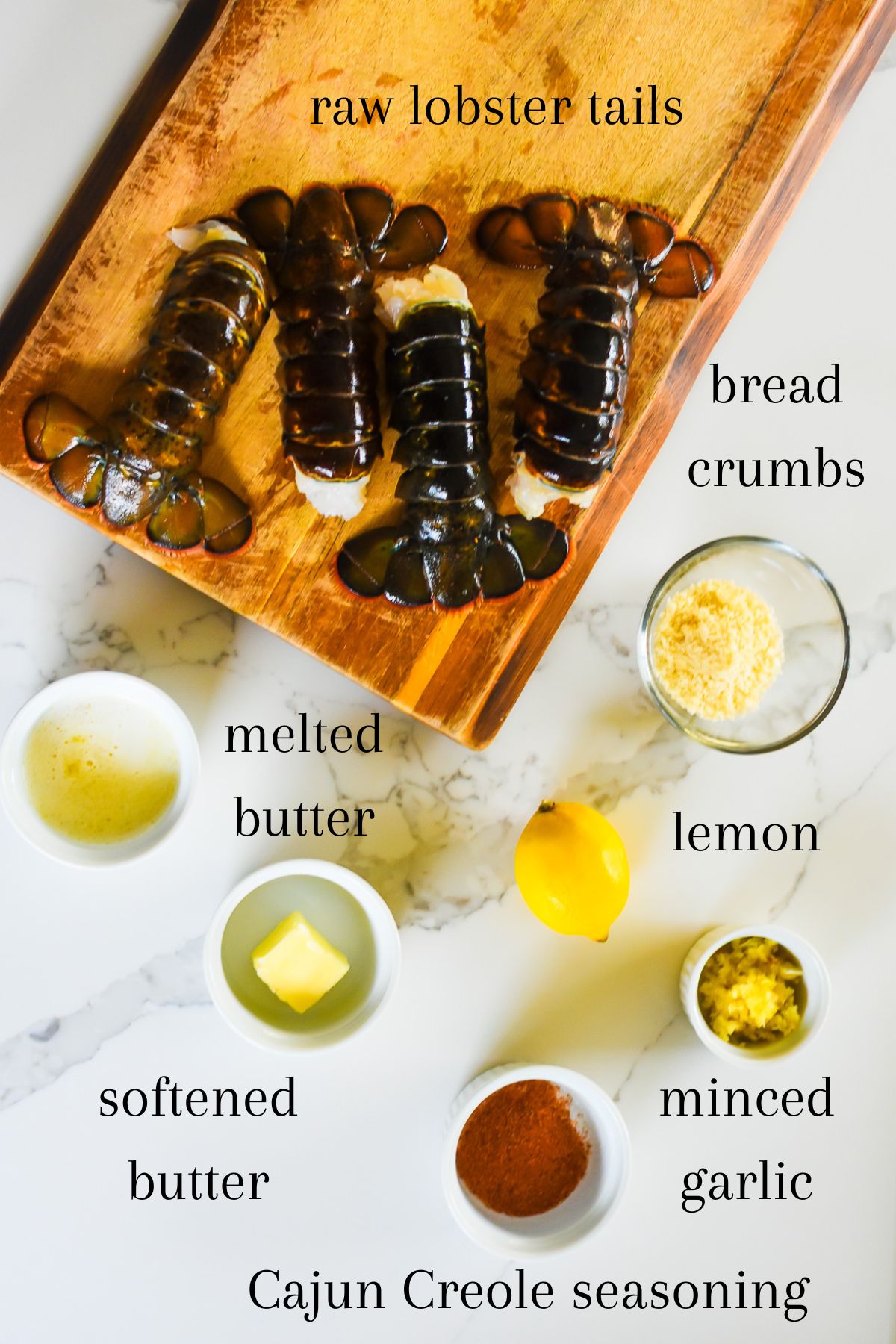 ingredients for baking lobster tails on granite counter top: fresh cold-water lobster tails, Panko bread crumbs, melted butter, softened butter, fresh lemon, minced garlic, and Creole Cajun seasonings.