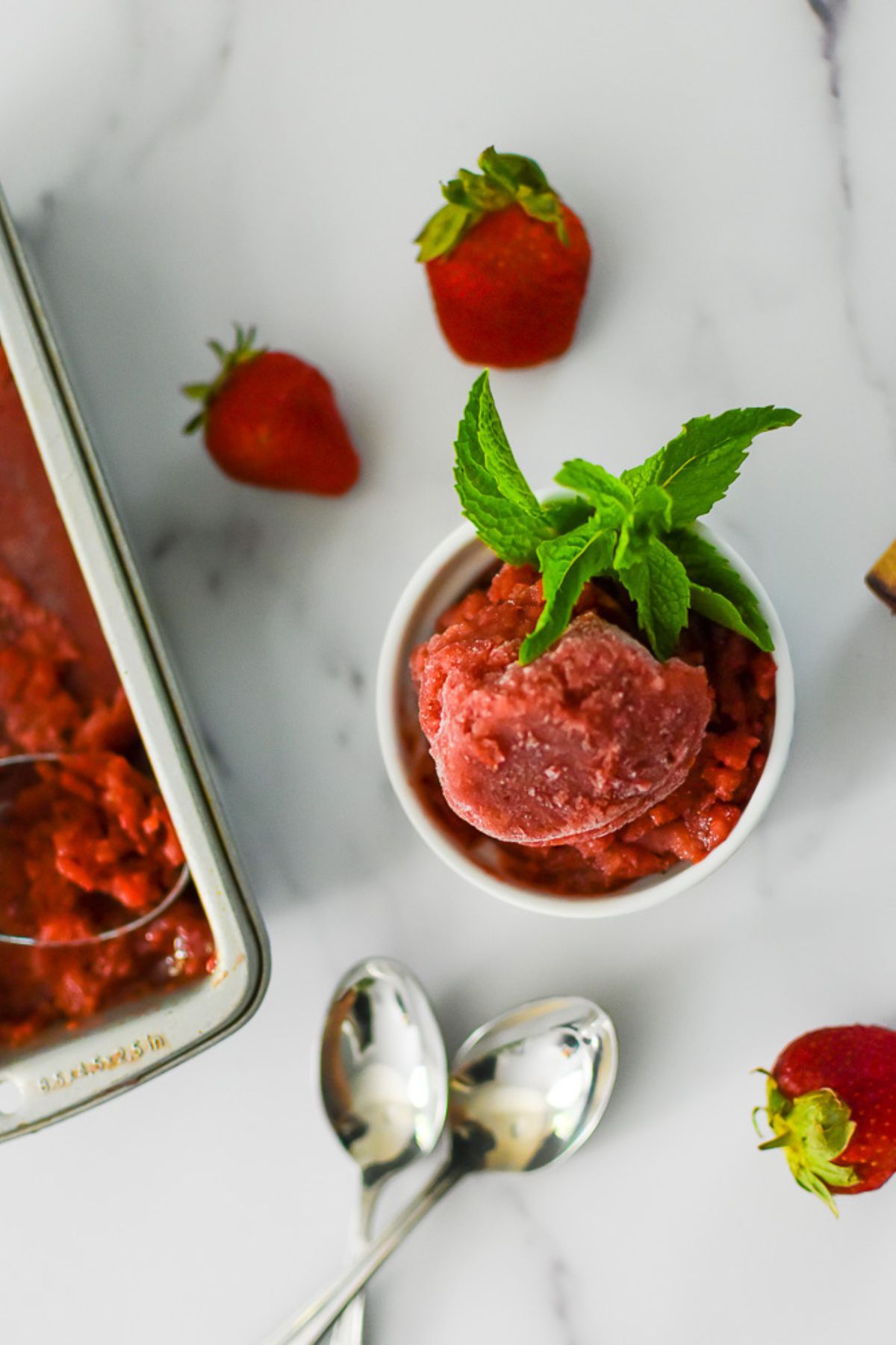 scoops of red wine strawberry sorbet in white ramekin garnished with fresh mint.
