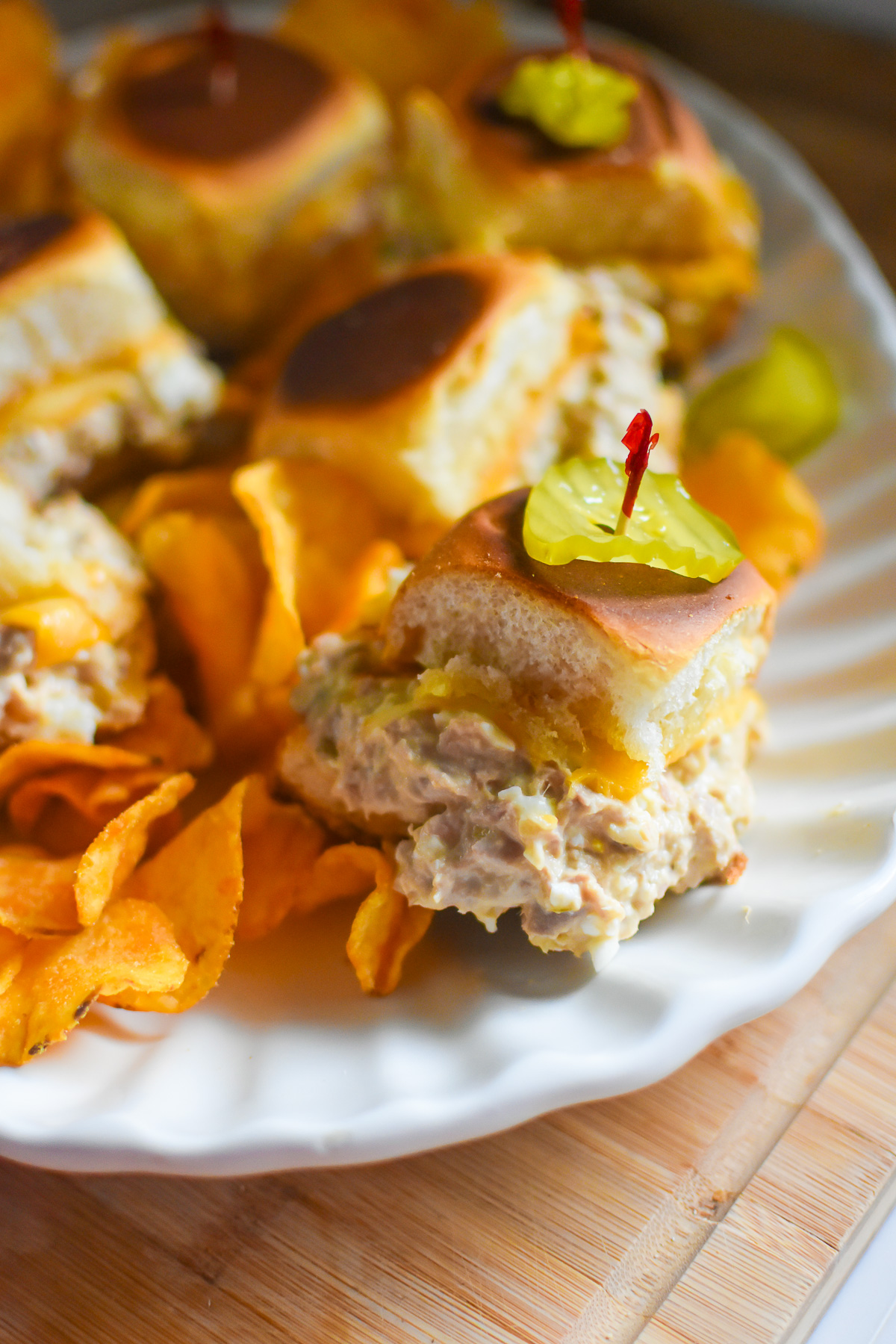 plate of oven baked tuna melt sliders garnished with pickle slices and cocktail toothpicks.