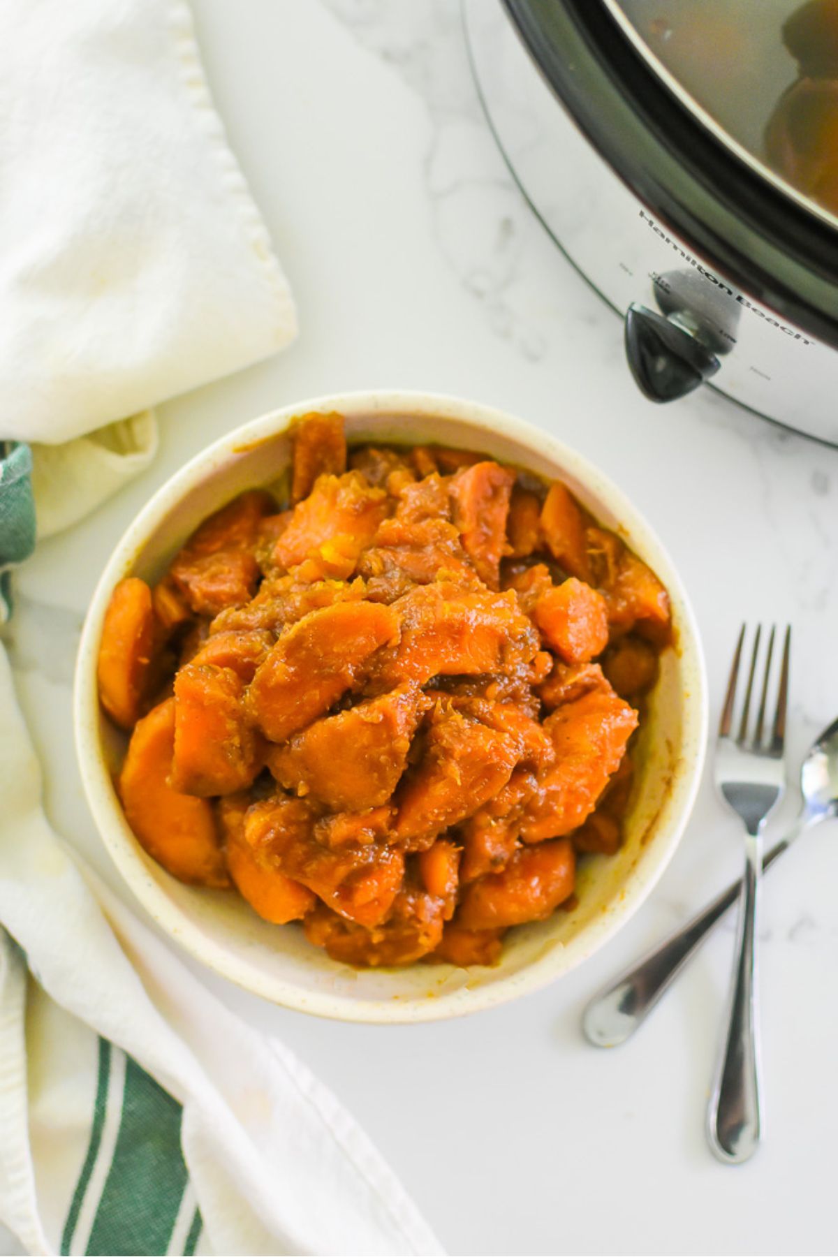 slow cooker candied yams in bowl next to crock pot.