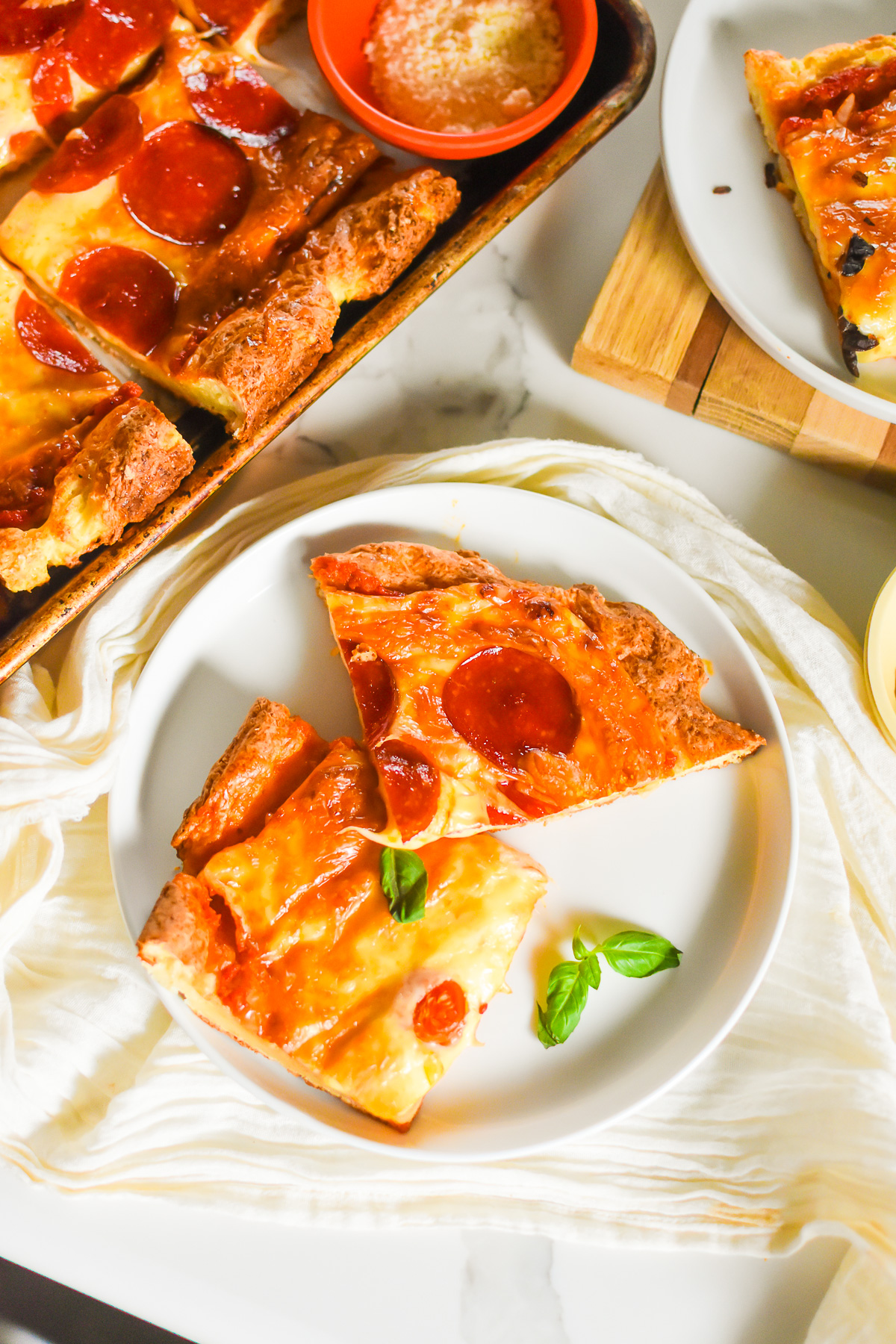 plate with slices of high-protein pizza topped with pepperoni and tomato basil.